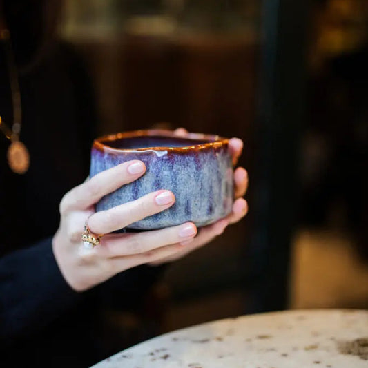 Person holding a ceramic cup with a blurred background