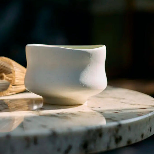 White ceramic cup on a textured surface with a blurred natural background
