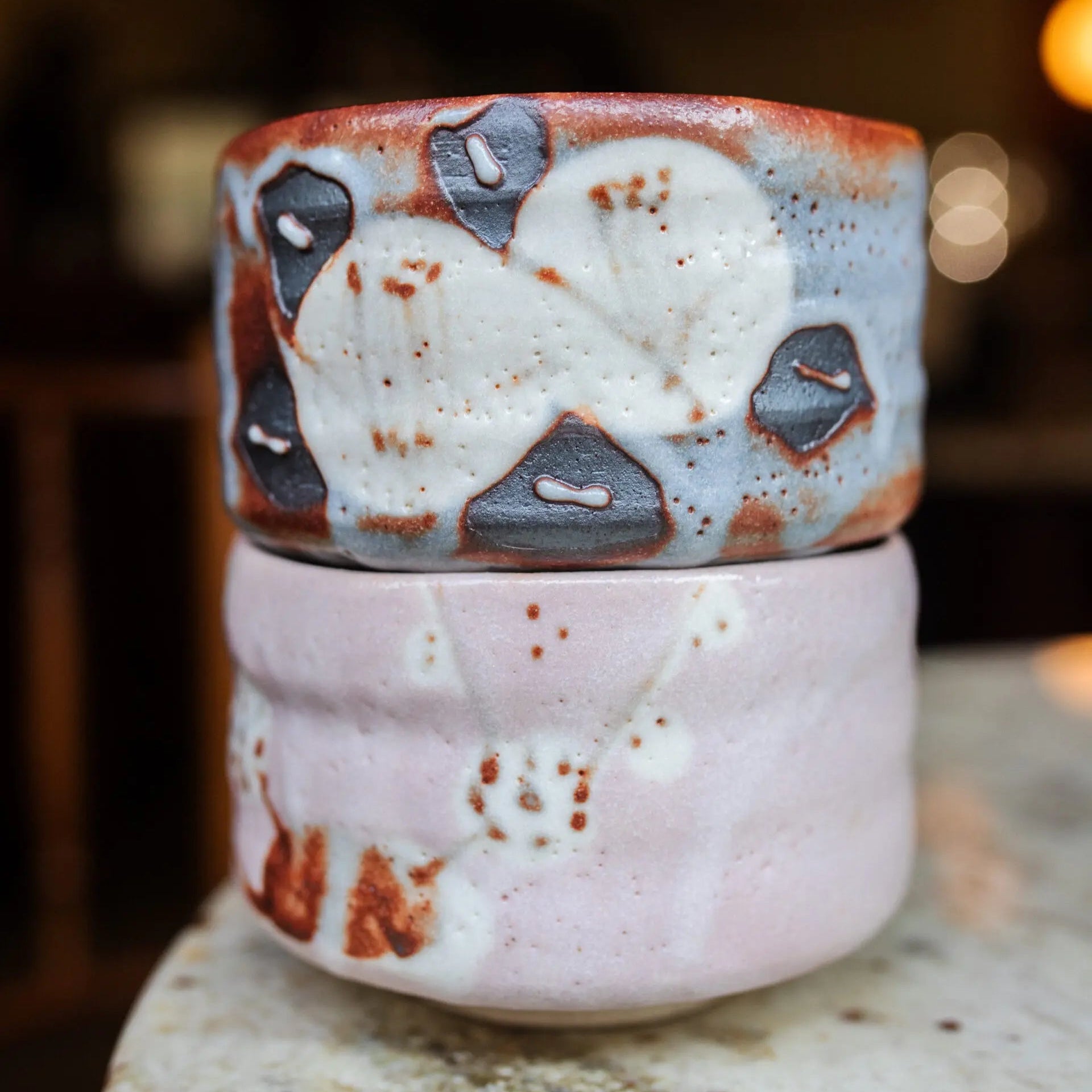 Two ceramic containers with abstract designs stacked on a marble surface.