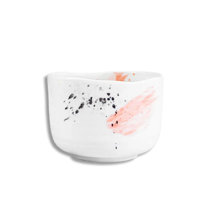 White ceramic bowl with black speckles and pink abstract design on a white background