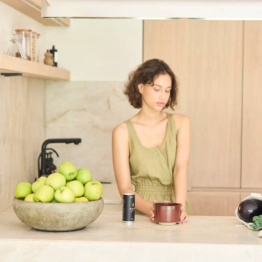 Woman standing in a modern kitchen with a bowl of apples on the counter.